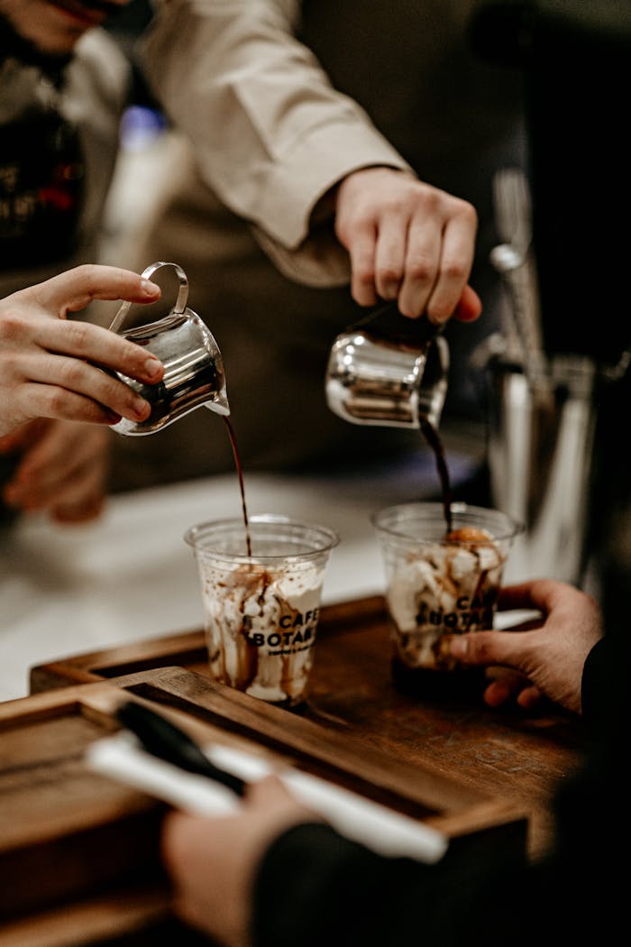 about-us Close-up of baristas pouring coffee into cups at a cafe counter.